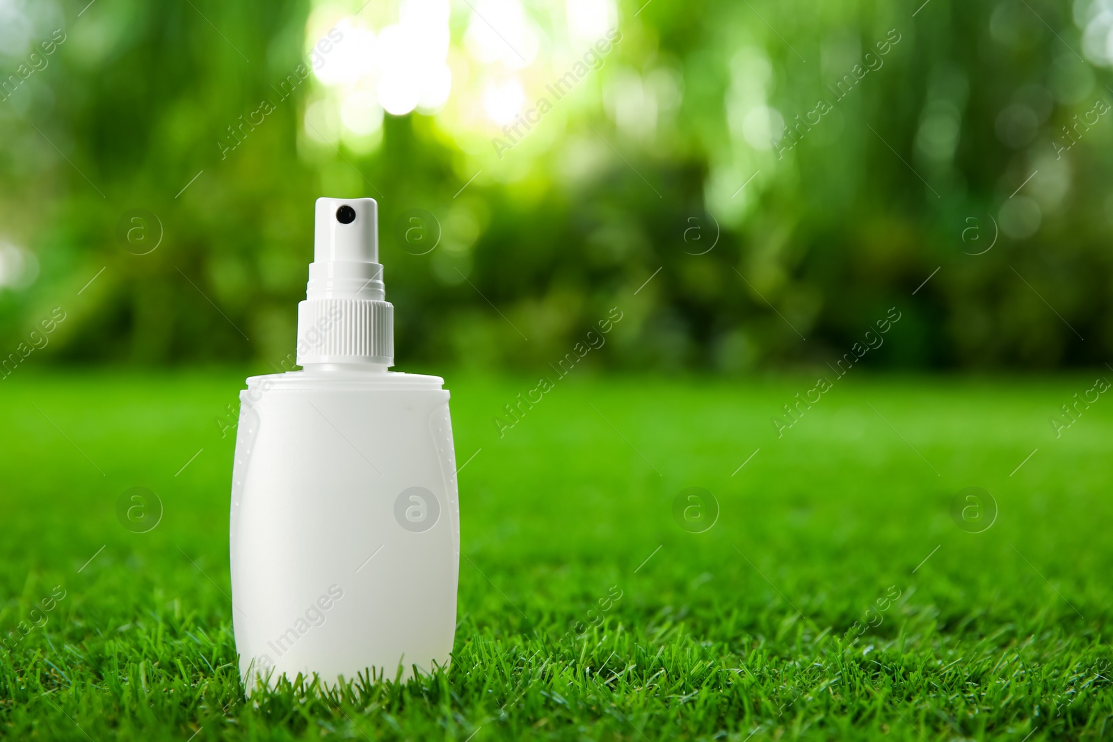 Photo of Bottle of insect repellent spray on green grass. Space for text