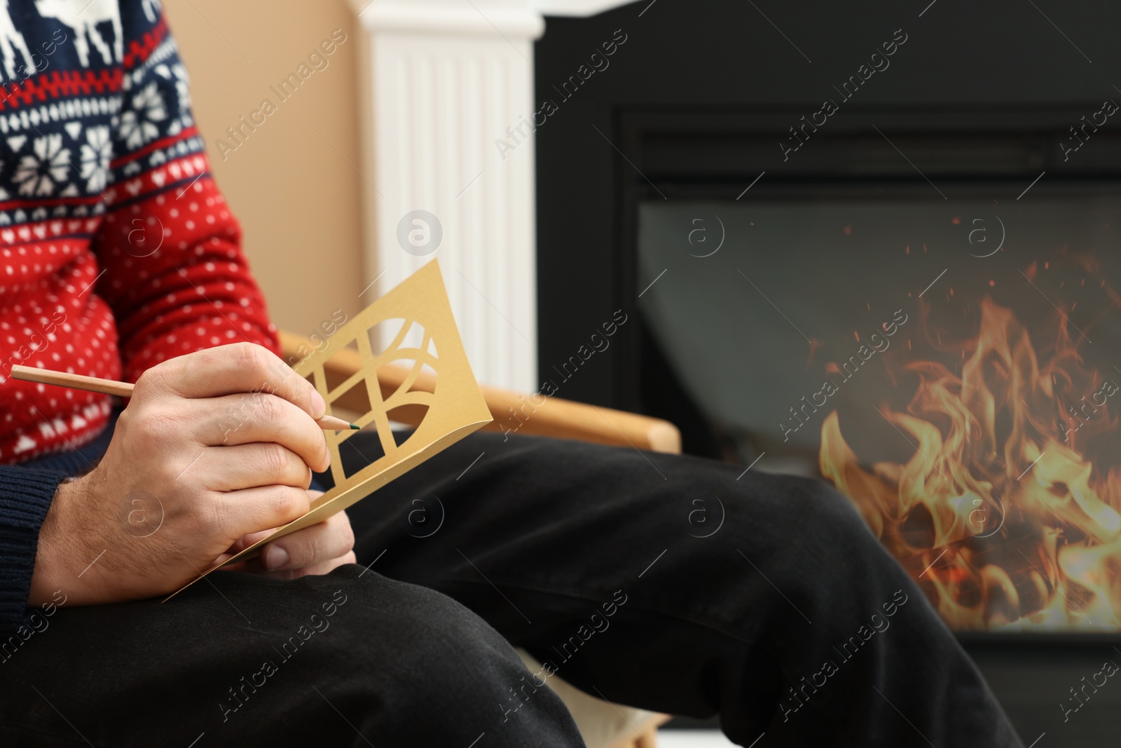 Photo of Man writing wishes in Christmas greeting card in living room, closeup