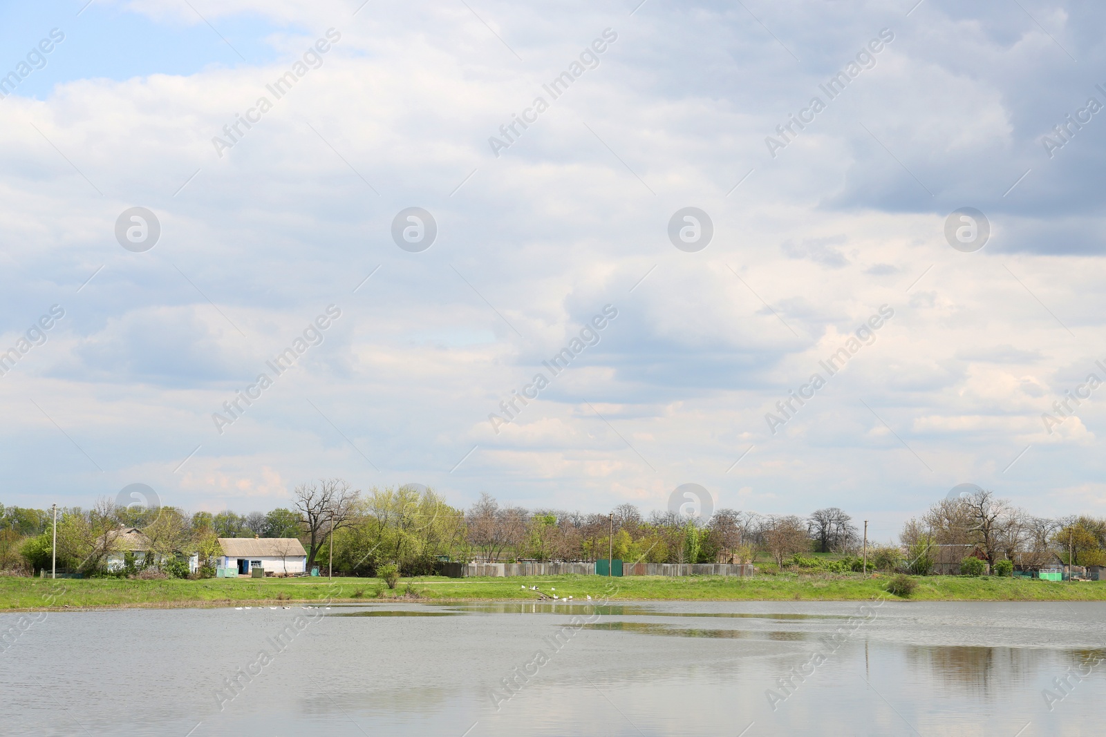 Photo of River near village under sky with clouds. Picturesque landscape