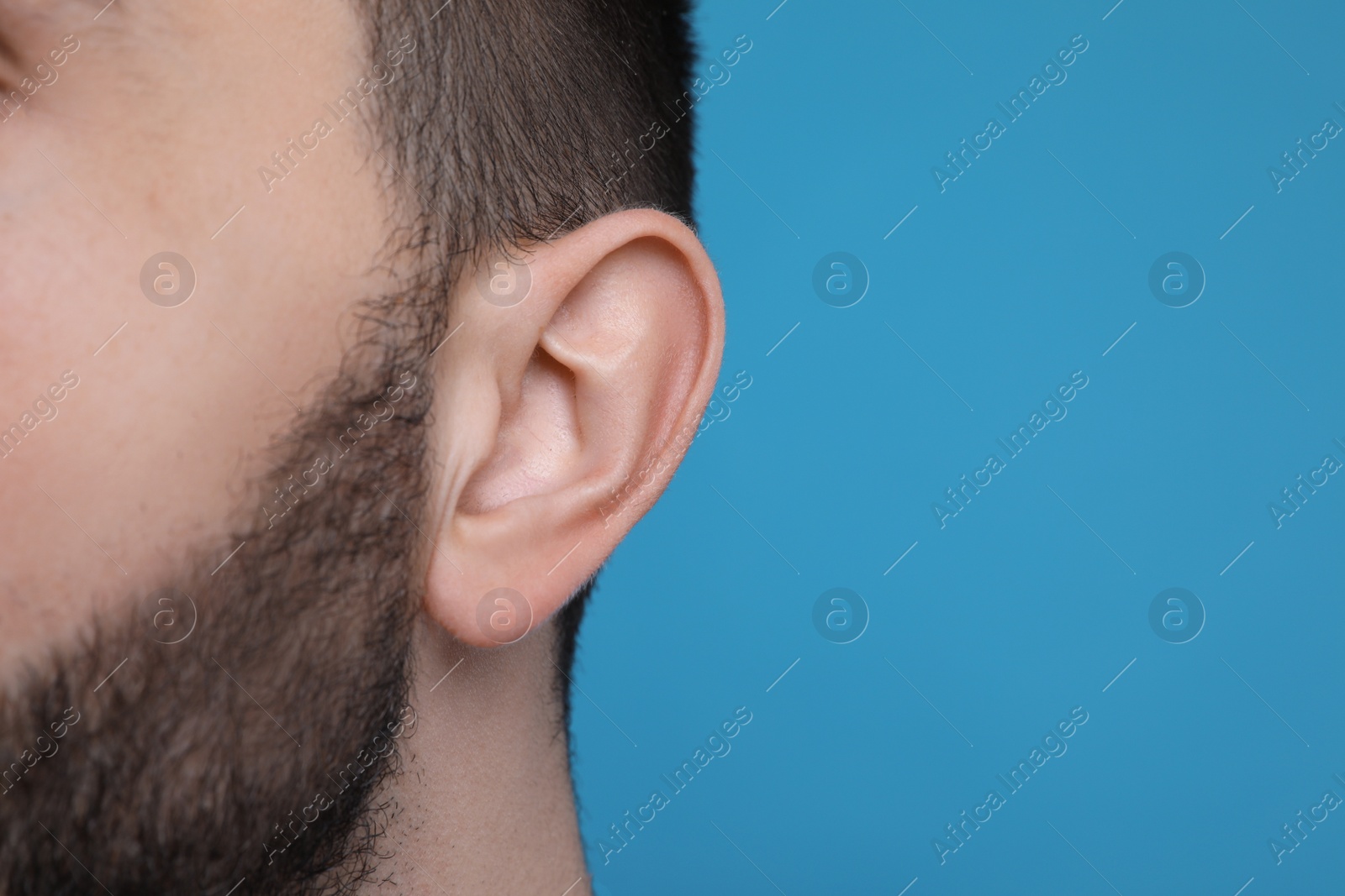 Photo of Man on light blue background, closeup of ear. Space for text