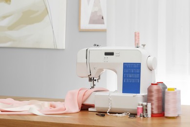 Photo of Sewing machine with fabric and craft accessories on wooden table indoors