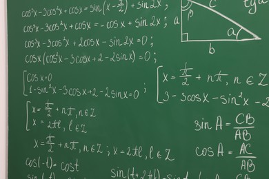Photo of Many different math formulas written on green chalkboard