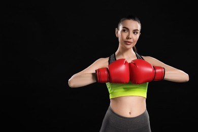 Photo of Portrait of beautiful woman in boxing gloves on black background. Space for text
