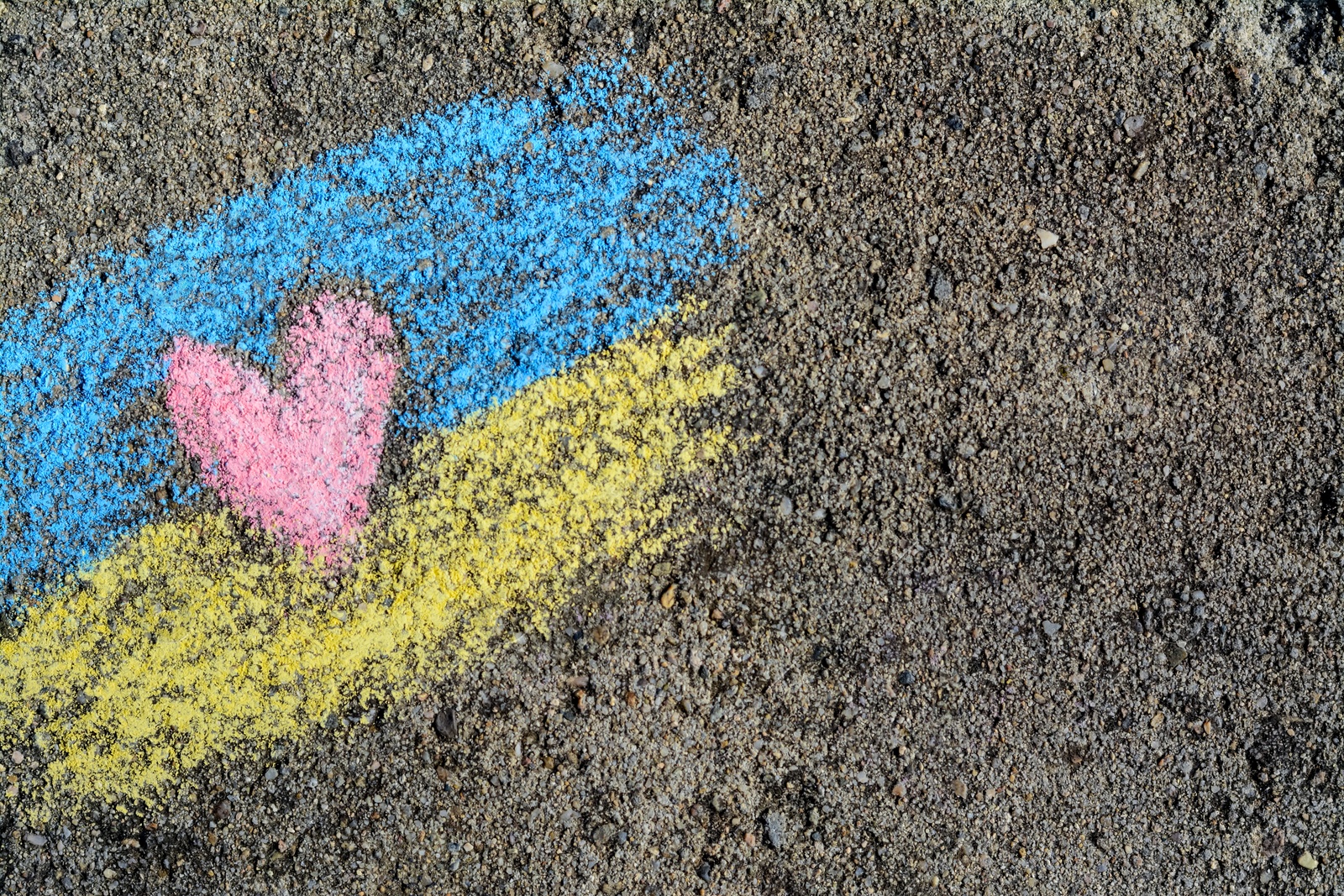 Photo of National flag of Ukraine with heart drawn by color chalk on asphalt, top view. Space for text