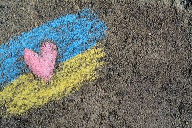 Photo of National flag of Ukraine with heart drawn by color chalk on asphalt, top view. Space for text