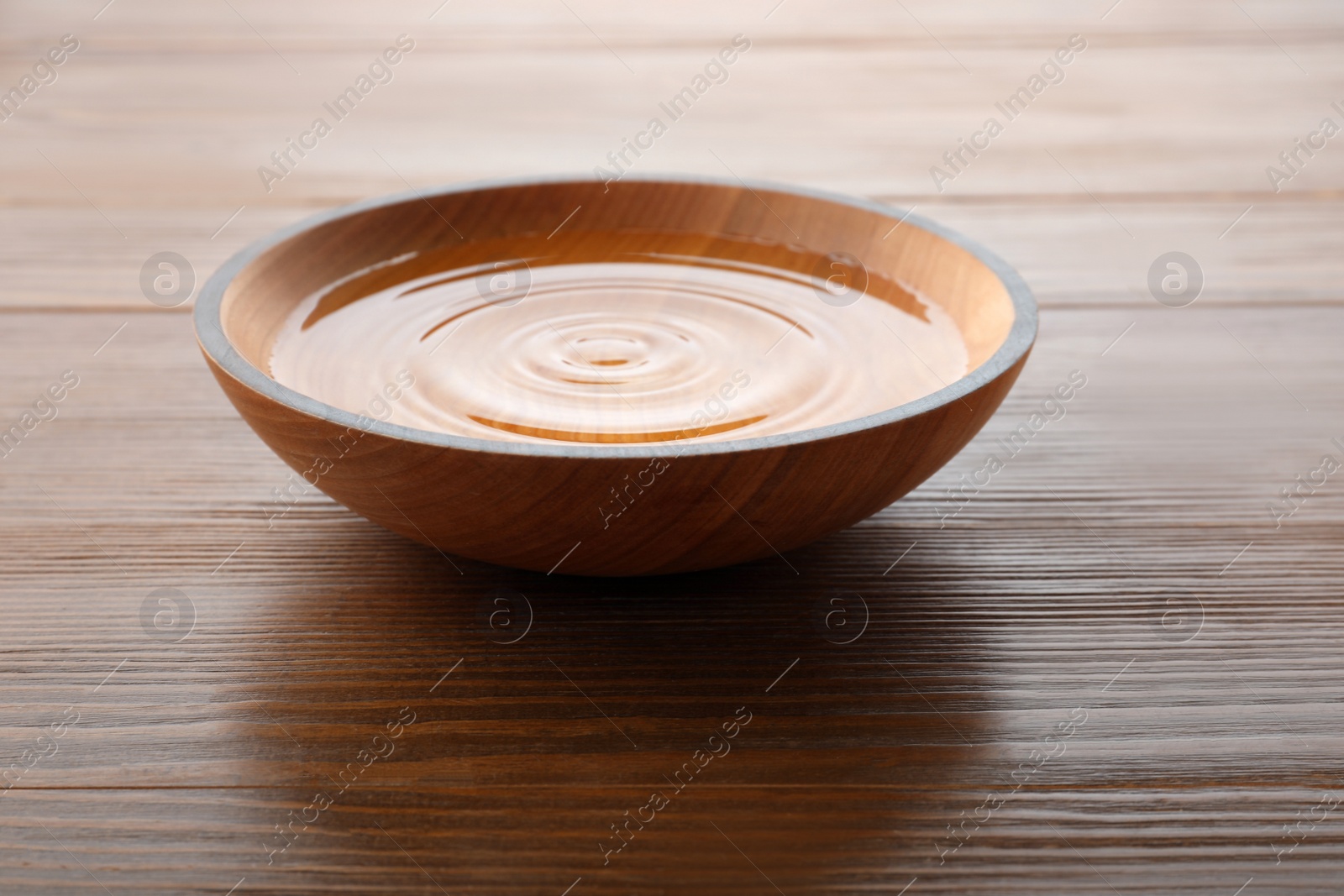 Photo of Bowl with pure water on wooden table