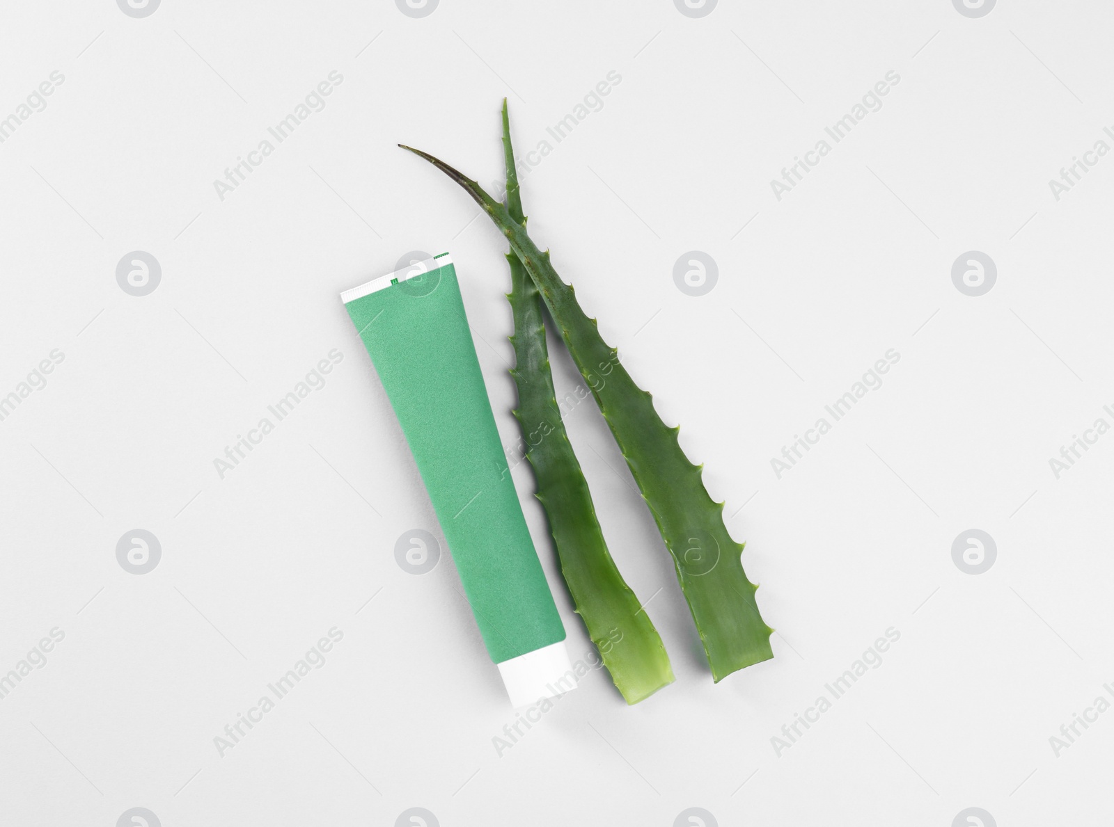 Photo of Tube of toothpaste and fresh aloe on white background, top view