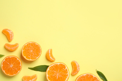 Flat lay composition with fresh ripe tangerines and leaves on light yellow background, space for text. Citrus fruit