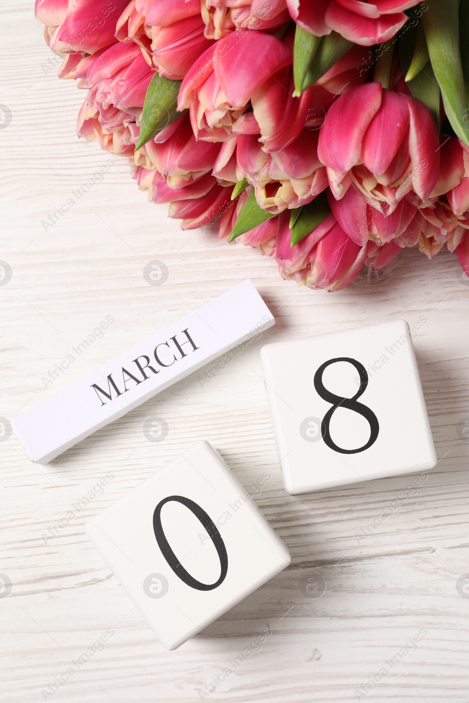 Photo of International Women's day - 8th of March. Block calendar and bouquet of beautiful tulips on white wooden table, flat lay