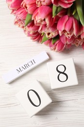 Photo of International Women's day - 8th of March. Block calendar and bouquet of beautiful tulips on white wooden table, flat lay