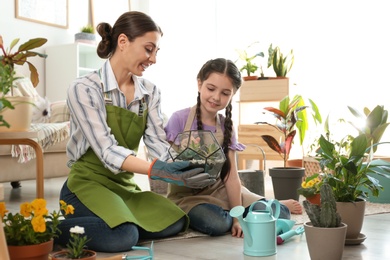 Photo of Mother and daughter taking care of plants on floor at home