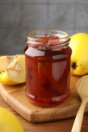 Tasty homemade quince jam in jar and fruits on wooden table