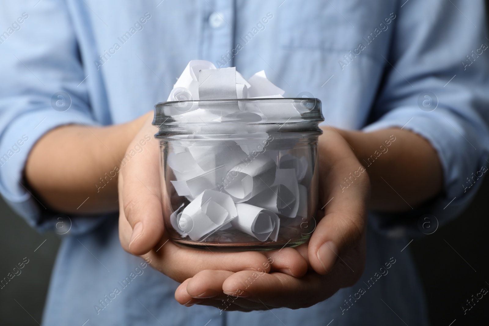 Photo of Woman holding glass jar with paper pieces, closeup on hands