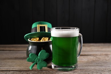 Photo of St. Patrick's day celebration. Green beer, leprechaun hat, pot of gold and decorative clover leaf on wooden table