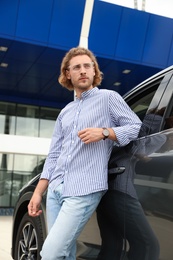 Photo of Attractive young man near luxury car outdoors