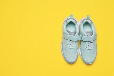 Photo of Pair of comfortable sports shoes on yellow background, flat lay. Space for text