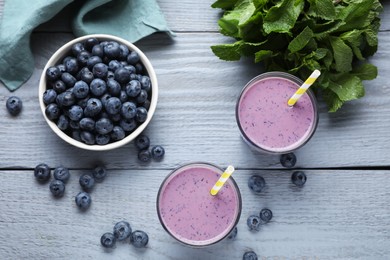 Photo of Freshly made blueberry smoothie on grey wooden table, flat lay
