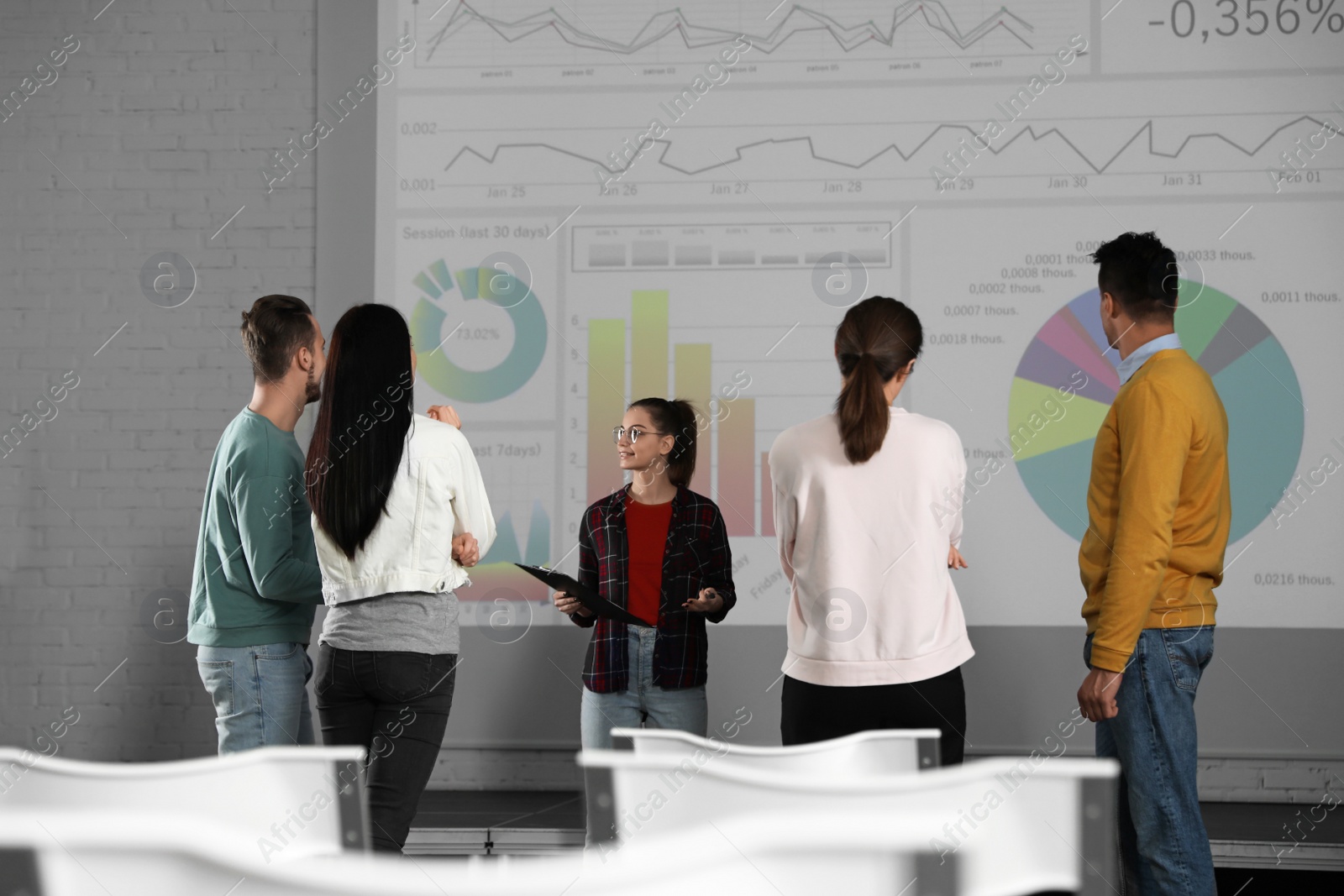 Photo of Young people having business training in conference room with projection screen