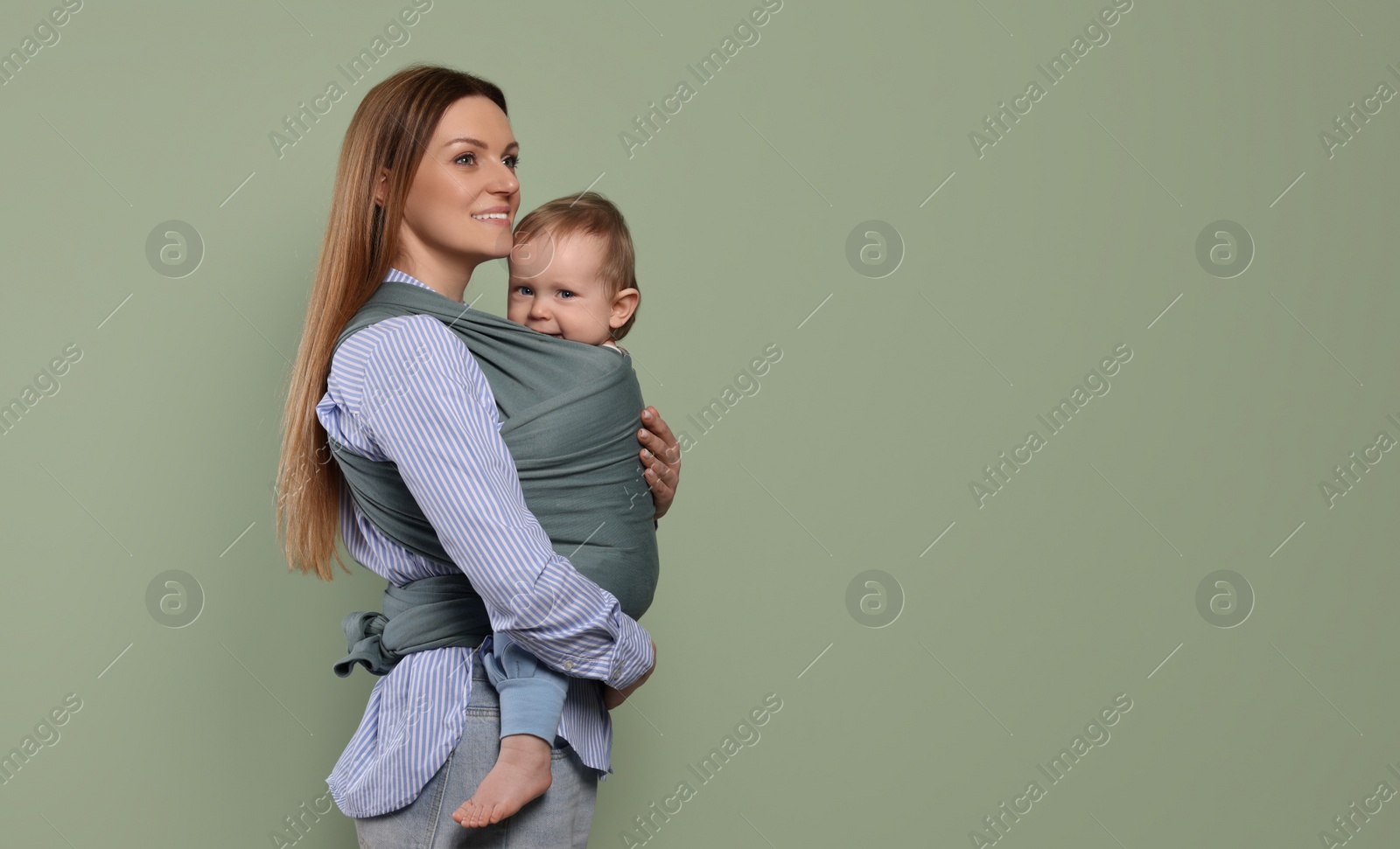 Photo of Mother holding her child in baby wrap on olive background. Space for text