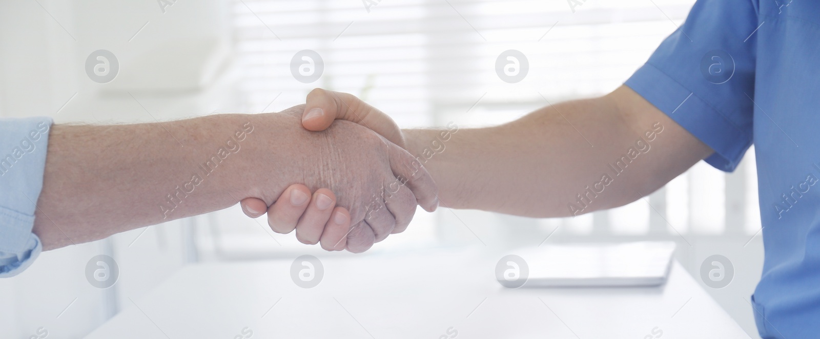 Image of Doctor and senior patient shaking hands in office, closeup. Banner design