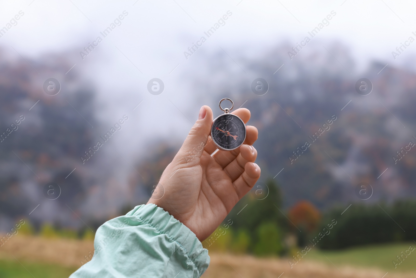 Photo of Woman using compass for navigation during journey in mountains, closeup