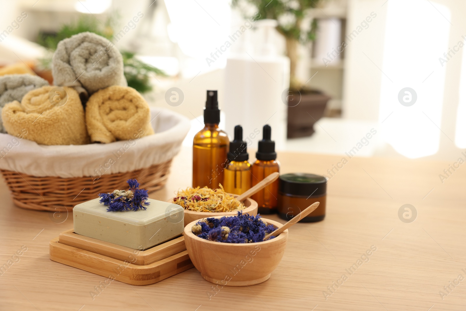 Photo of Soap bar, dry flowers, bottles of essential oils, jar with cream and towels on wooden table indoors, space for text. Spa time