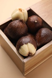 Photo of Wooden crate with fresh salak fruits on beige background, closeup