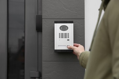 Man ringing intercom with camera near building entrance, closeup