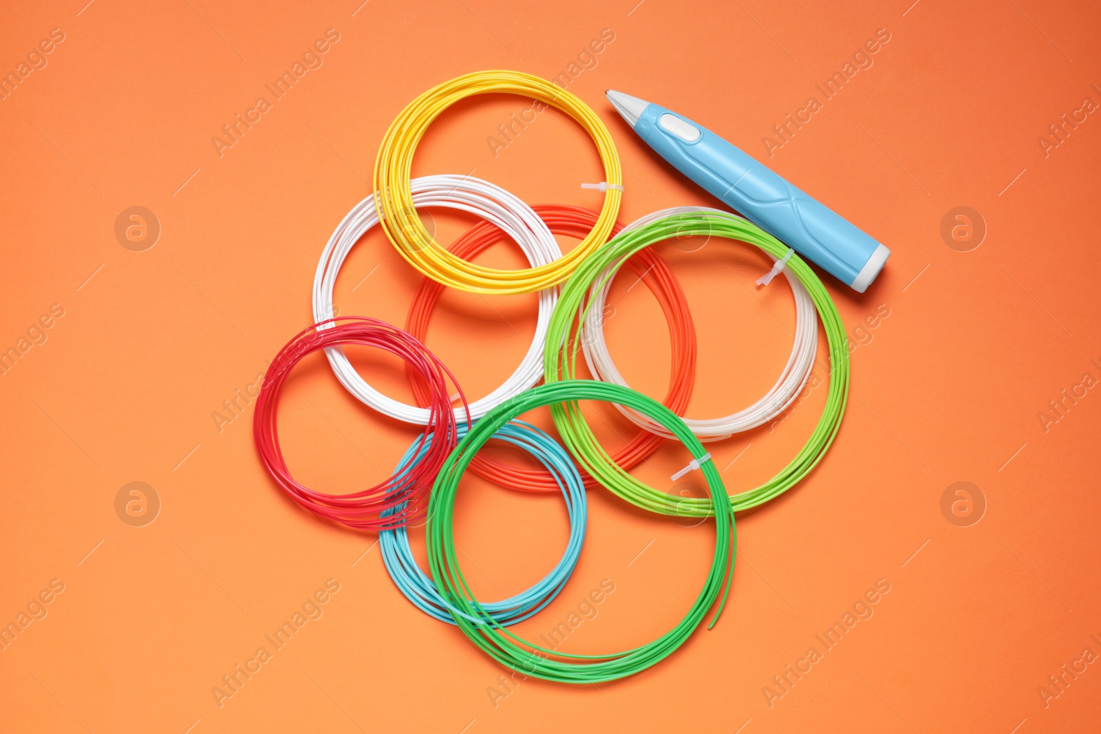 Photo of Stylish 3D pen and colorful plastic filaments on orange background, flat lay