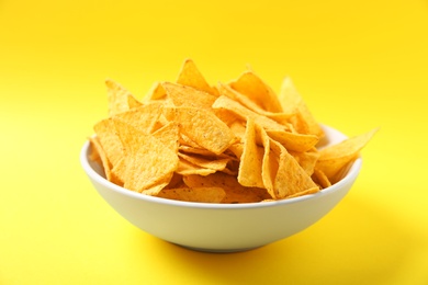 Tasty mexican nachos chips in bowl on yellow background