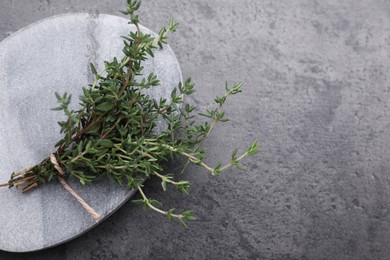 Photo of Bunch of fresh thyme on grey table, top view. Space for text