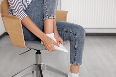 Photo of Woman suffering from foot pain on chair indoors, closeup