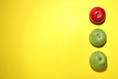 Photo of Ripe red and green apples on yellow background, flat lay. Space for text