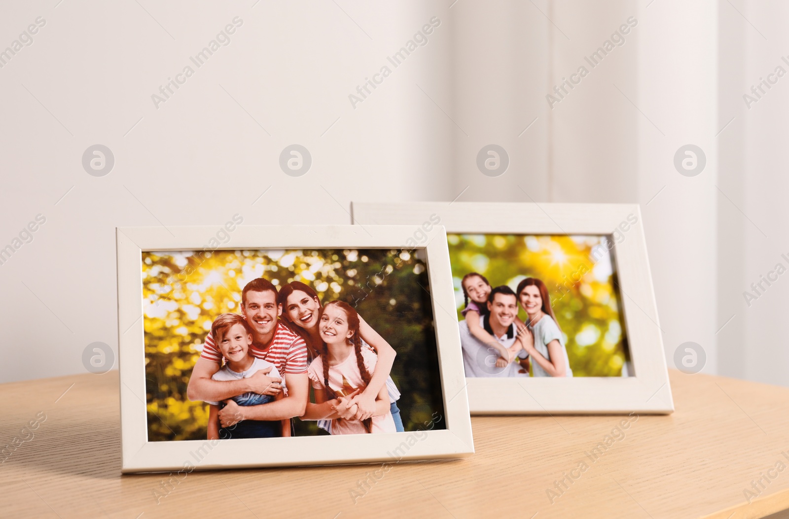 Photo of Frames with family photos on wooden table near white wall