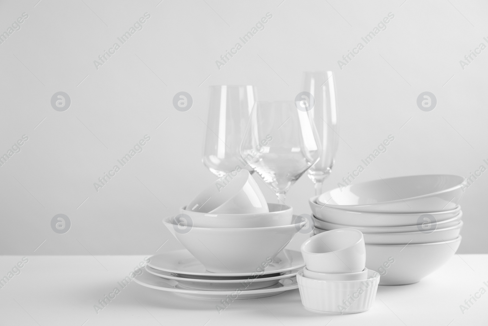 Photo of Set of clean dishes on white table