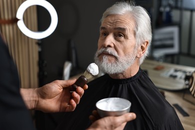 Photo of Professional barber working with client's mustache in barbershop