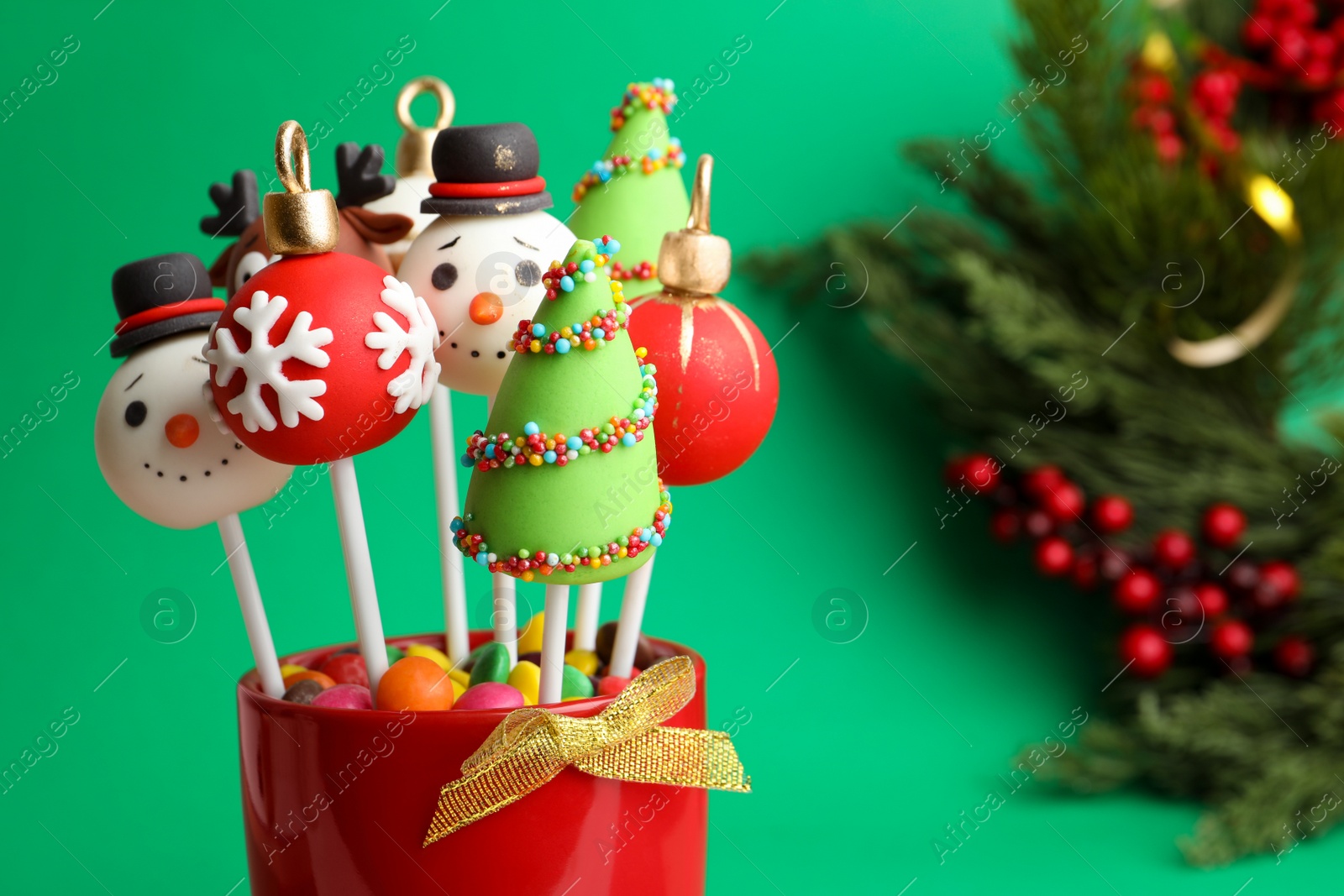 Photo of Delicious Christmas themed cake pops on green background, closeup. Space for text