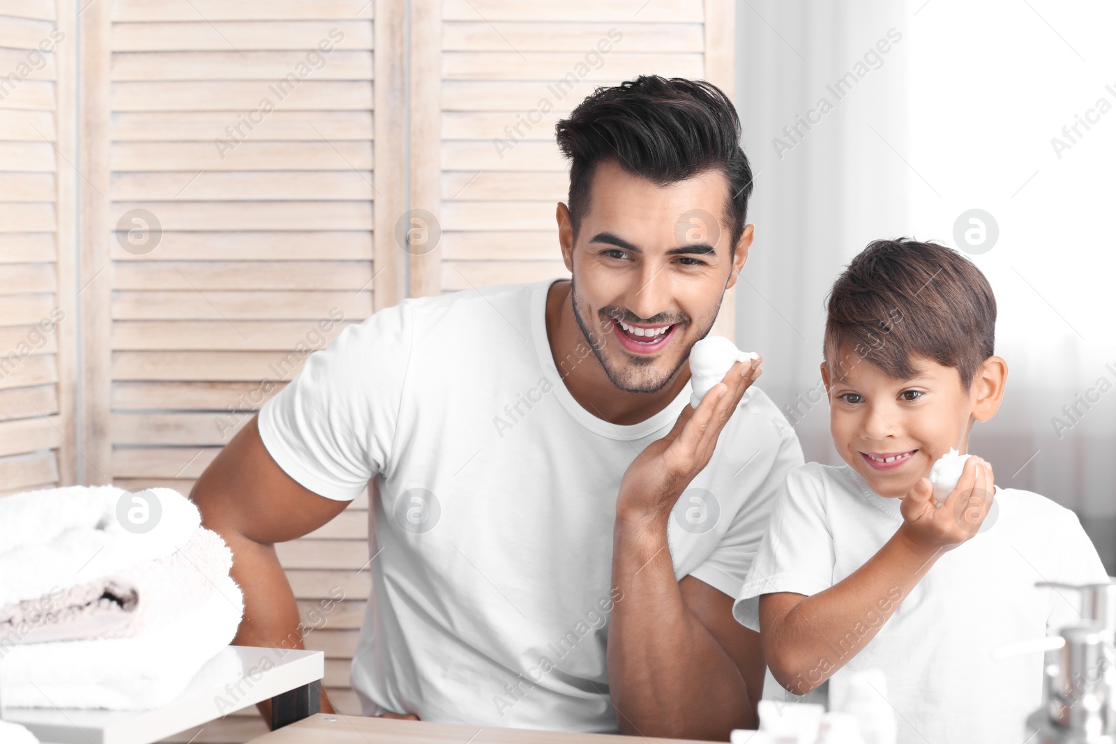 Photo of Father and son having fun while shaving in bathroom