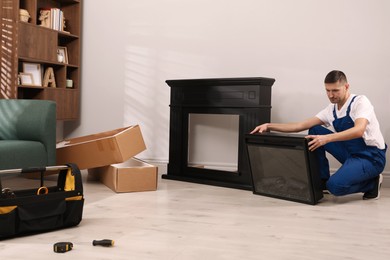 Photo of Professional technician installing electric fireplace in room