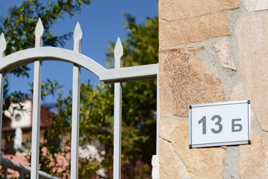Plate with number 13 on textured stone wall near metal gates