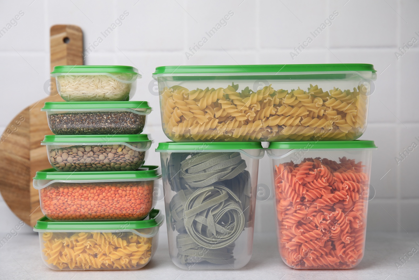 Photo of Plastic containers filled with food products on white table near tiled wall