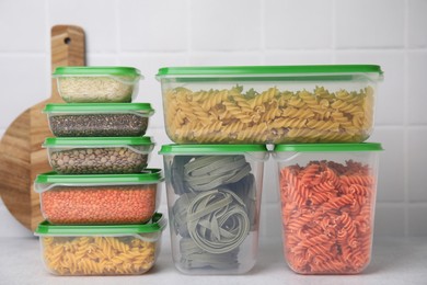 Photo of Plastic containers filled with food products on white table near tiled wall