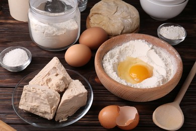 Compressed yeast, eggs, salt, dough and flour on wooden table