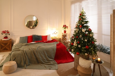 Beautiful decorated Christmas tree with fairy lights in bedroom. Interior design