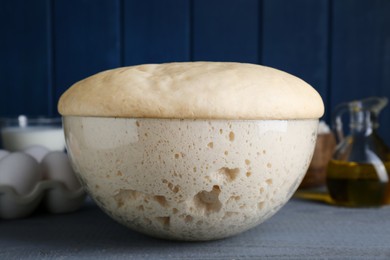 Bowl of fresh yeast dough on grey wooden table, closeup