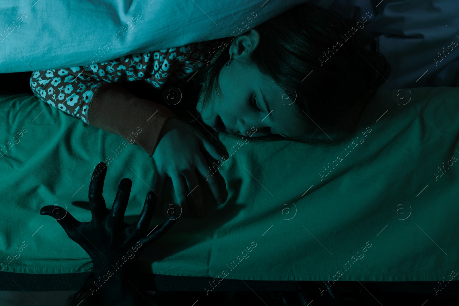 Photo of Childhood phobia. Scared girl looking at monster under bed indoors, closeup