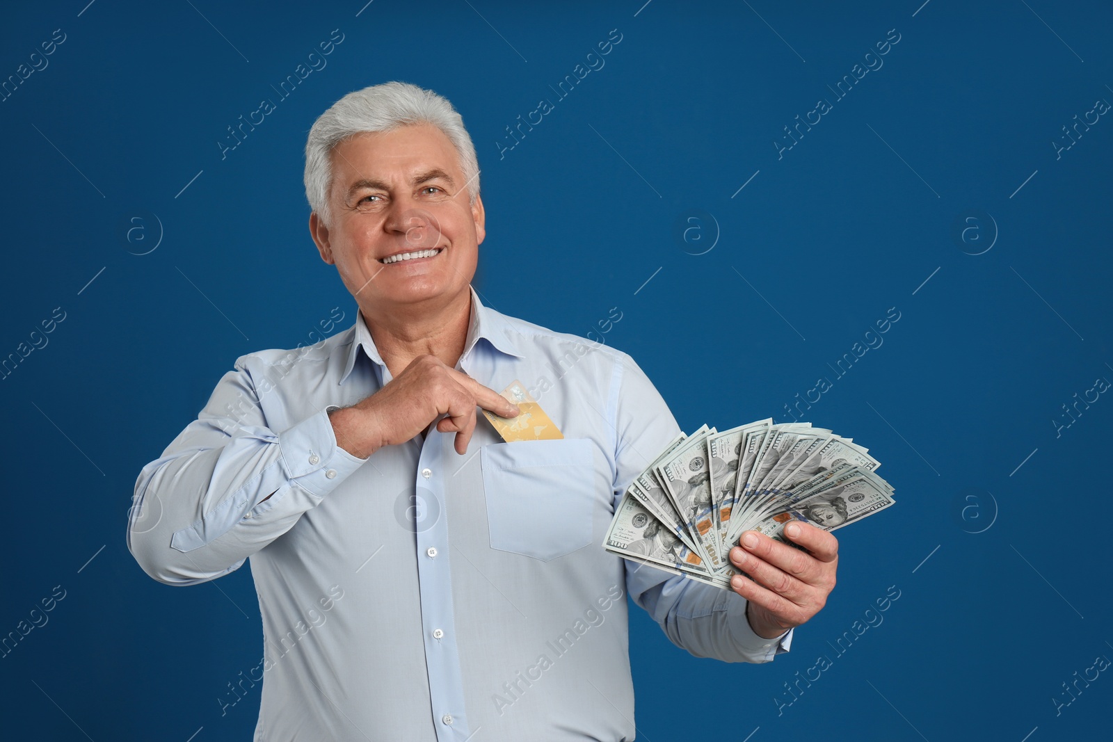 Photo of Happy senior man with cash money and credit card on blue background