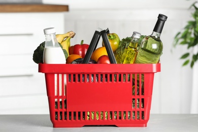 Photo of Shopping basket with grocery products on grey table indoors