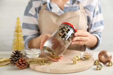 Woman making snow globe at light table, closeup