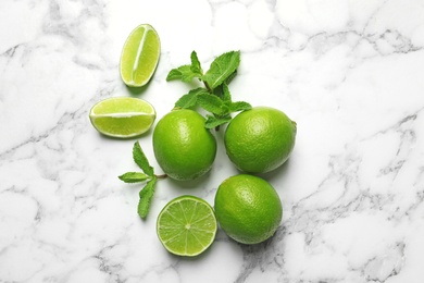 Photo of Fresh ripe limes on marble background, top view
